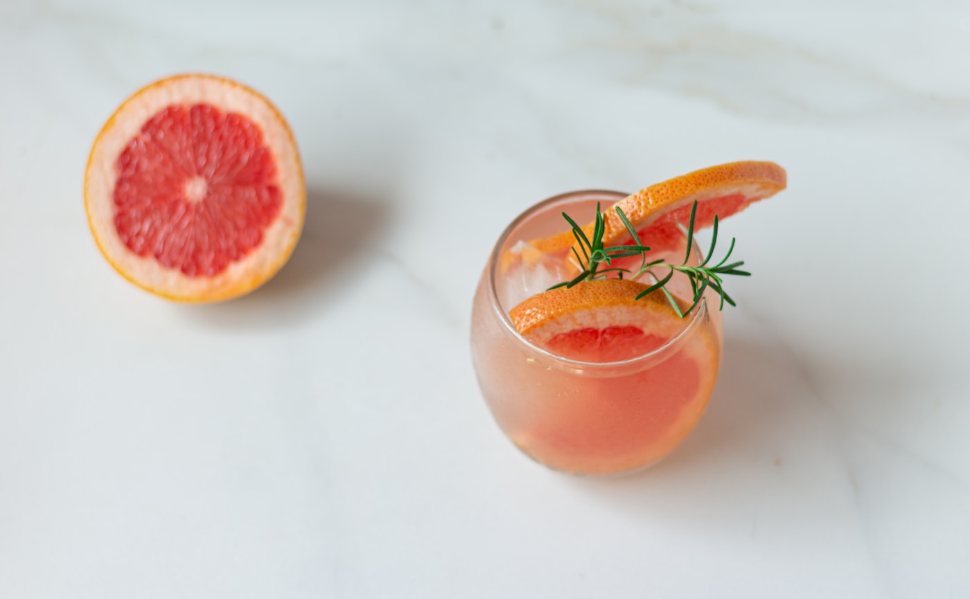Różowy grejpfrutowy spritz z gałązką rozmarynu i lodem